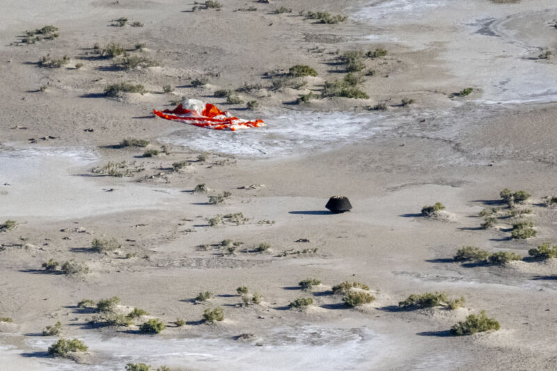 The OSIRIS-REx sample return capsule, with its main parachute nearby, shortly after landing in Utah on September 24, 2023.