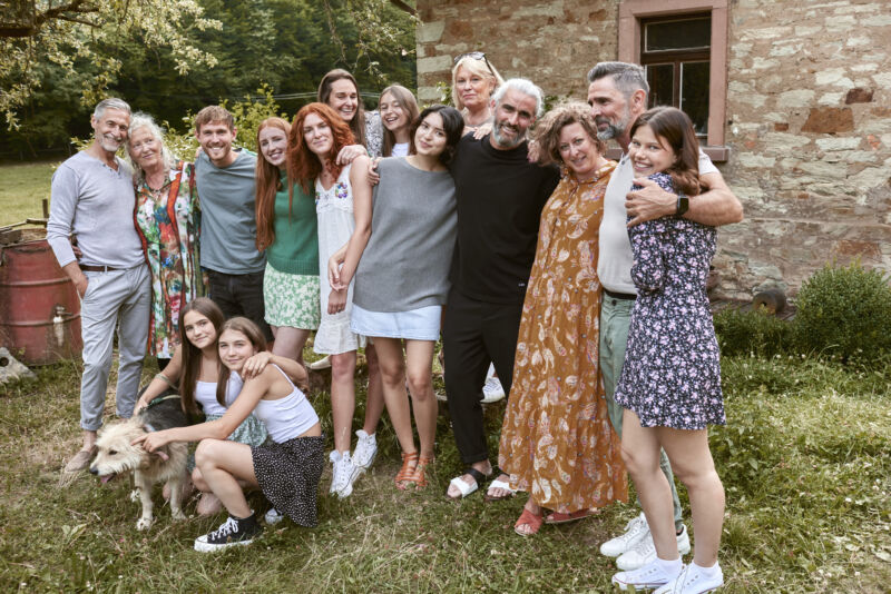 A family portrait taken outside of a stone house, with several generations of individuals.