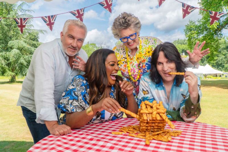 four smiling people at a festive picnic table munching on a tasty snack