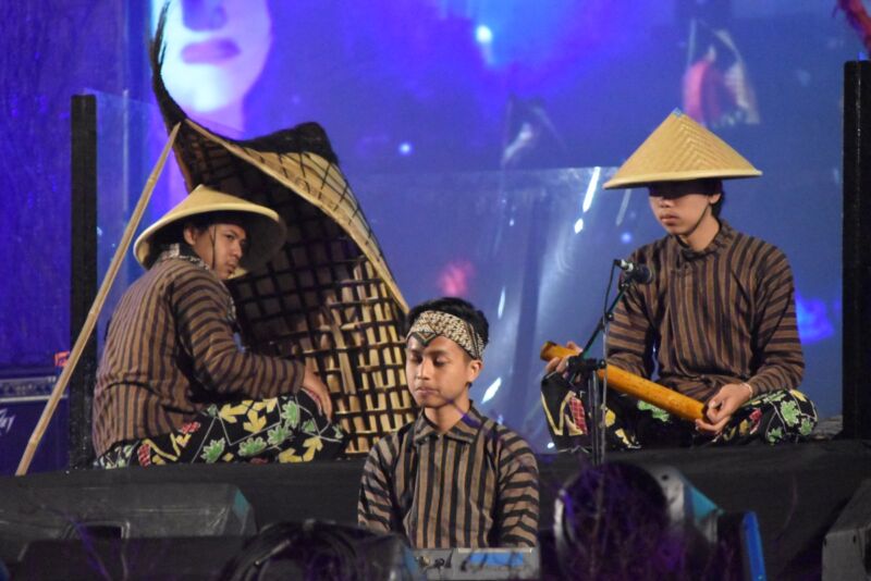 Indonesian performers onstage with one playing a bundengan