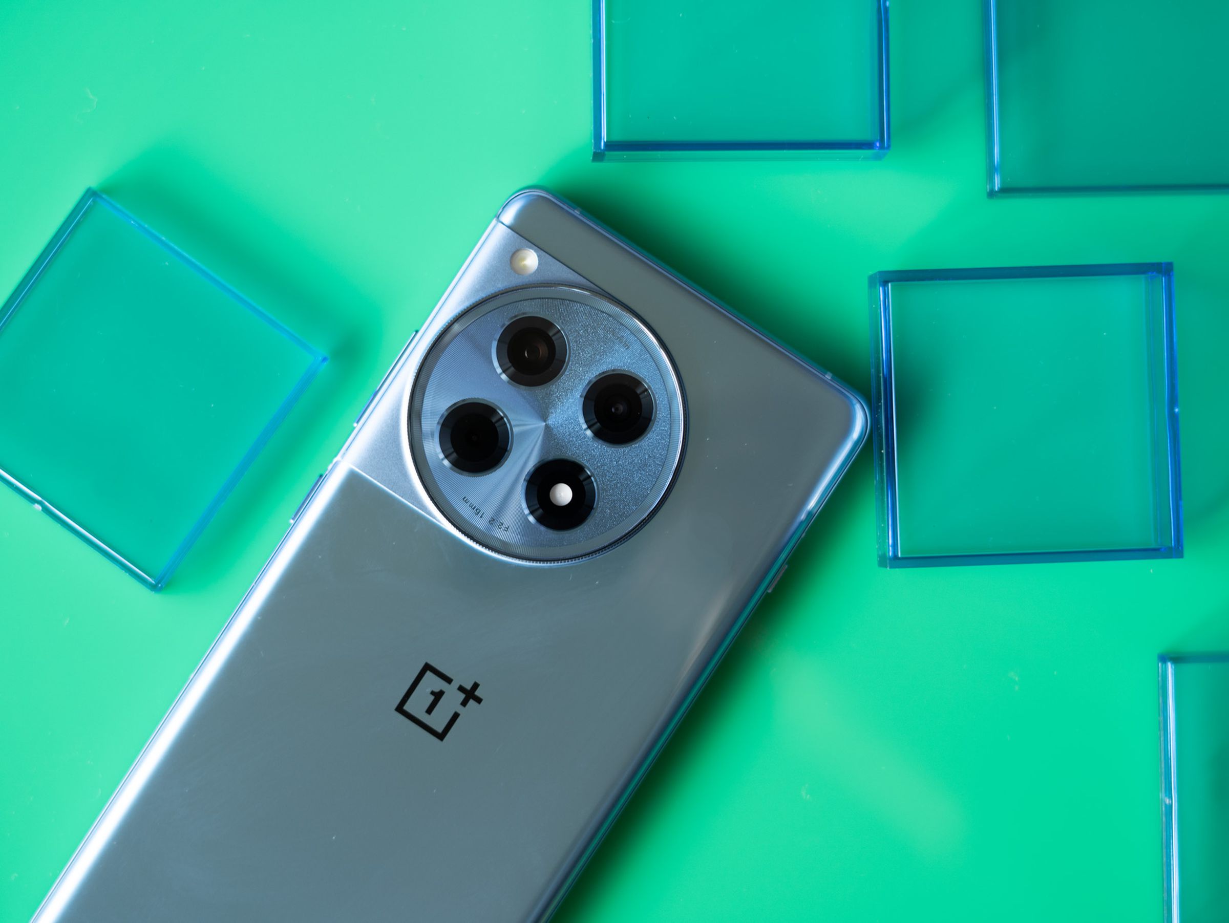 OnePlus 12R on a green background with blue translucent squares.