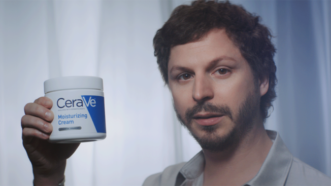 Michael Cera holding a tub of CeraVe moisturizer