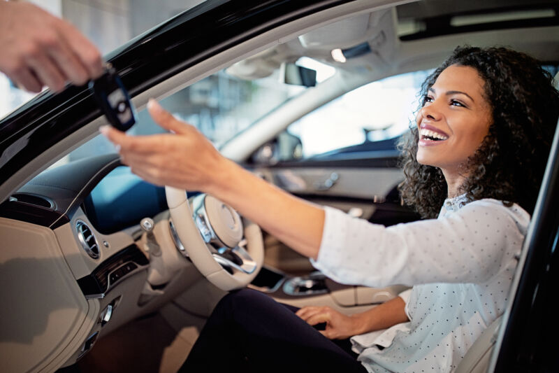 Car dealer is giving key for a new car to a woman