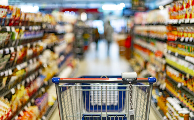 A shopping cart by a store shelf in a supermarket