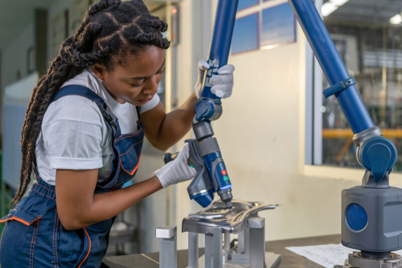 A woman performs maintenance on a robotic arm.