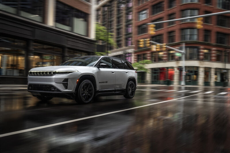 A silver Jeep Wagoneer S drives on a rainy city street