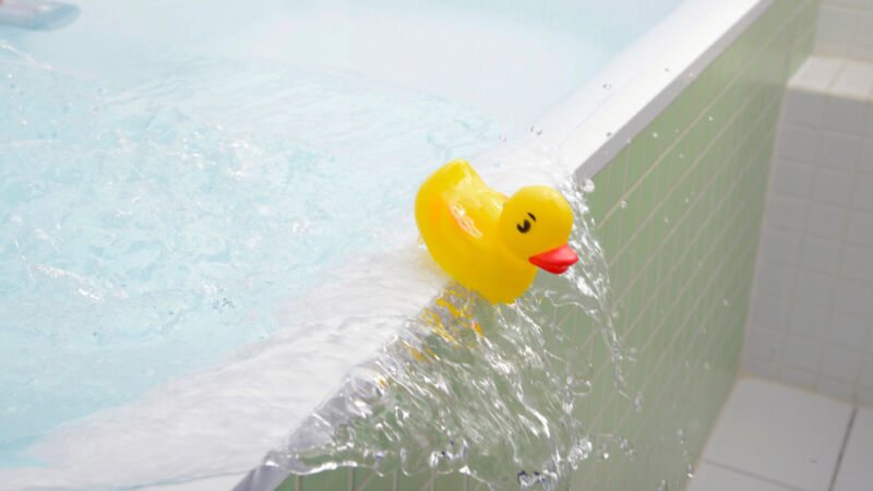 Rubber duck falling out of bath overflowing with water