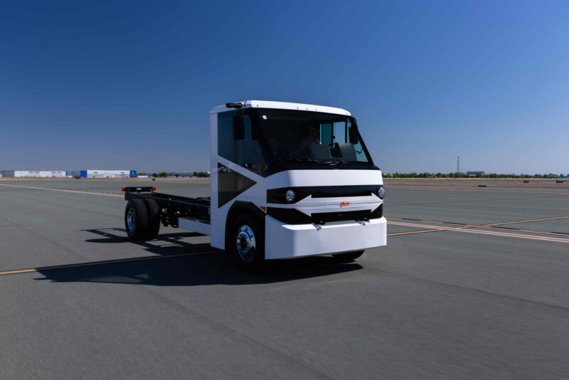 A white cab-chassis medium duty truck with a bare frame behind it