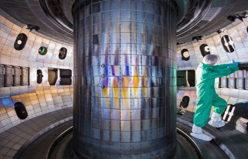 image of a person in protective clothing, standing in a circular area with lots of mirrored metal panels.