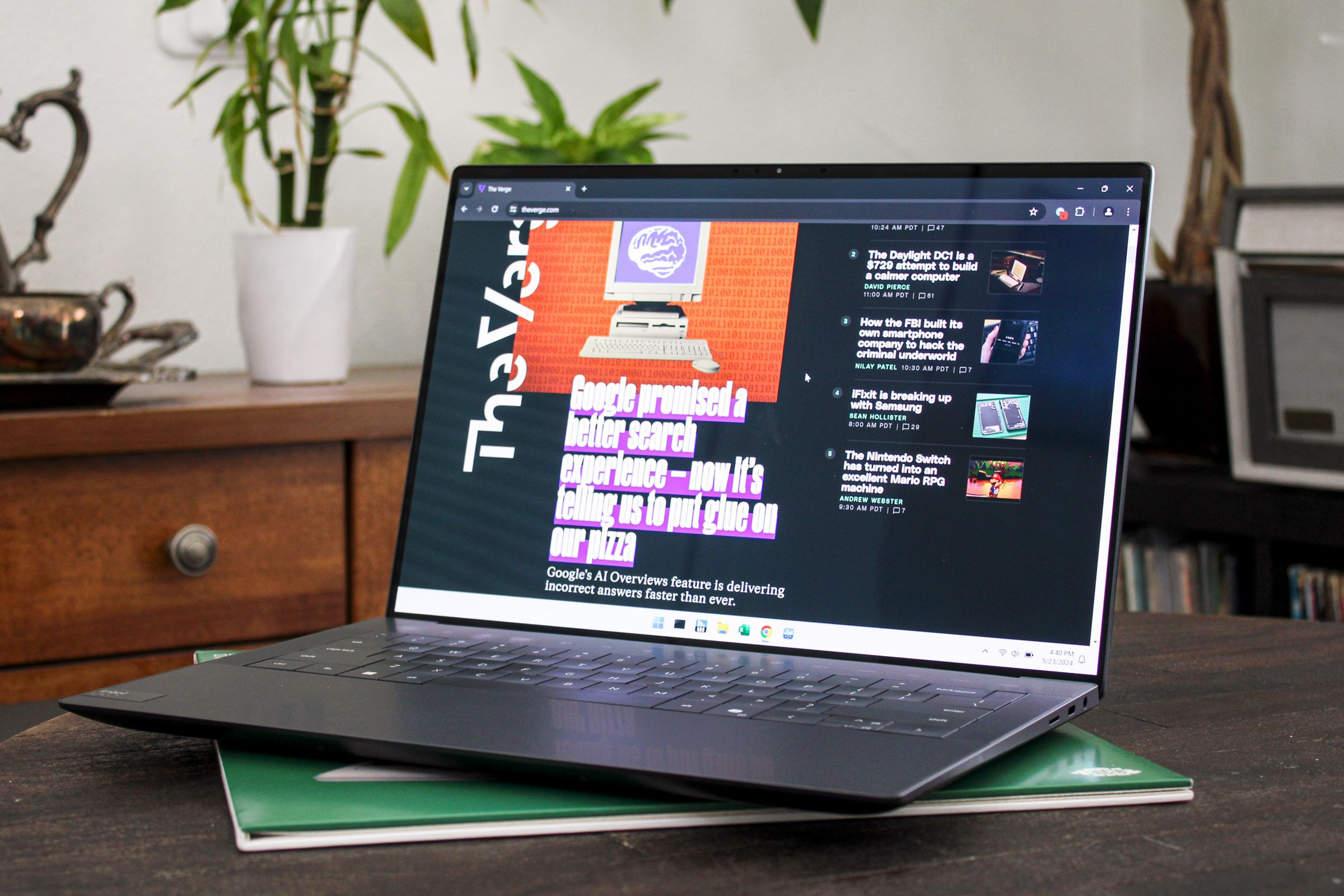 An open and powered on laptop sitting on top of a wood table with plants and furniture in the background.