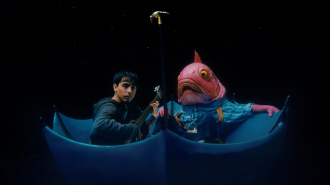 Iván Cornejo sitting in a boat with a man wearing a fish mask