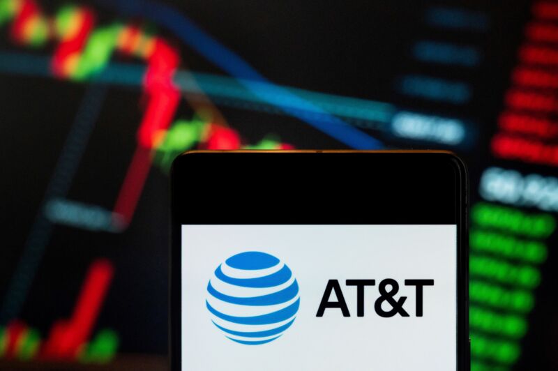 AT&T logo displayed on a smartphone with a stock exchange index graph in the background.