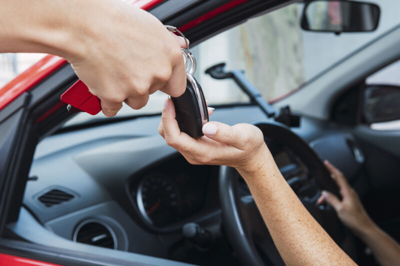 Salesman handling car keys to customer