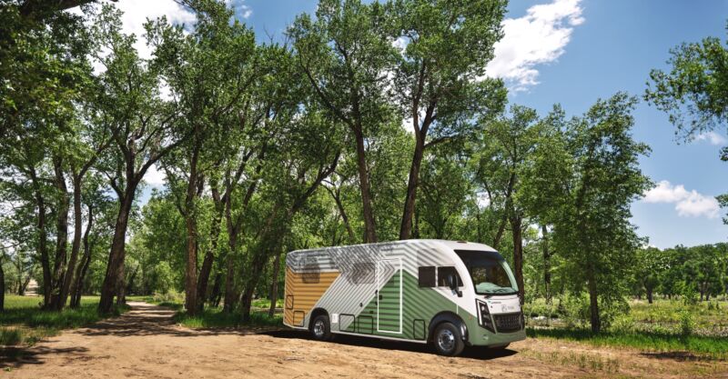 A white, green, and yellow RV parked next to some trees