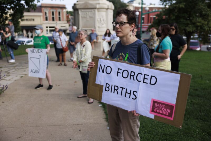 A woman holds a placard saying "No Forced Births" as abortion rights activists gather at the Monroe County Courthouse for a protest vigil a few hours before Indianas near total abortion ban goes into effect on September 15, 2022.