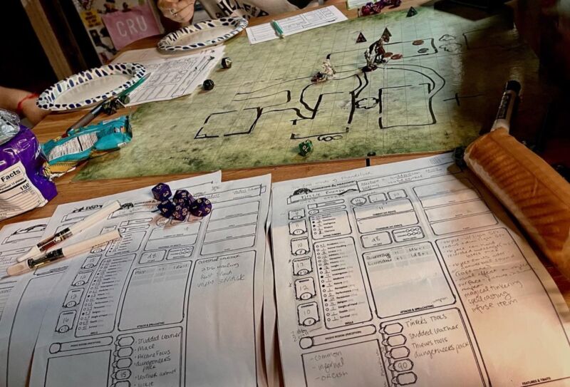 A Dungeons & Dragons game session featuring a map, miniatures, dice, and character sheets