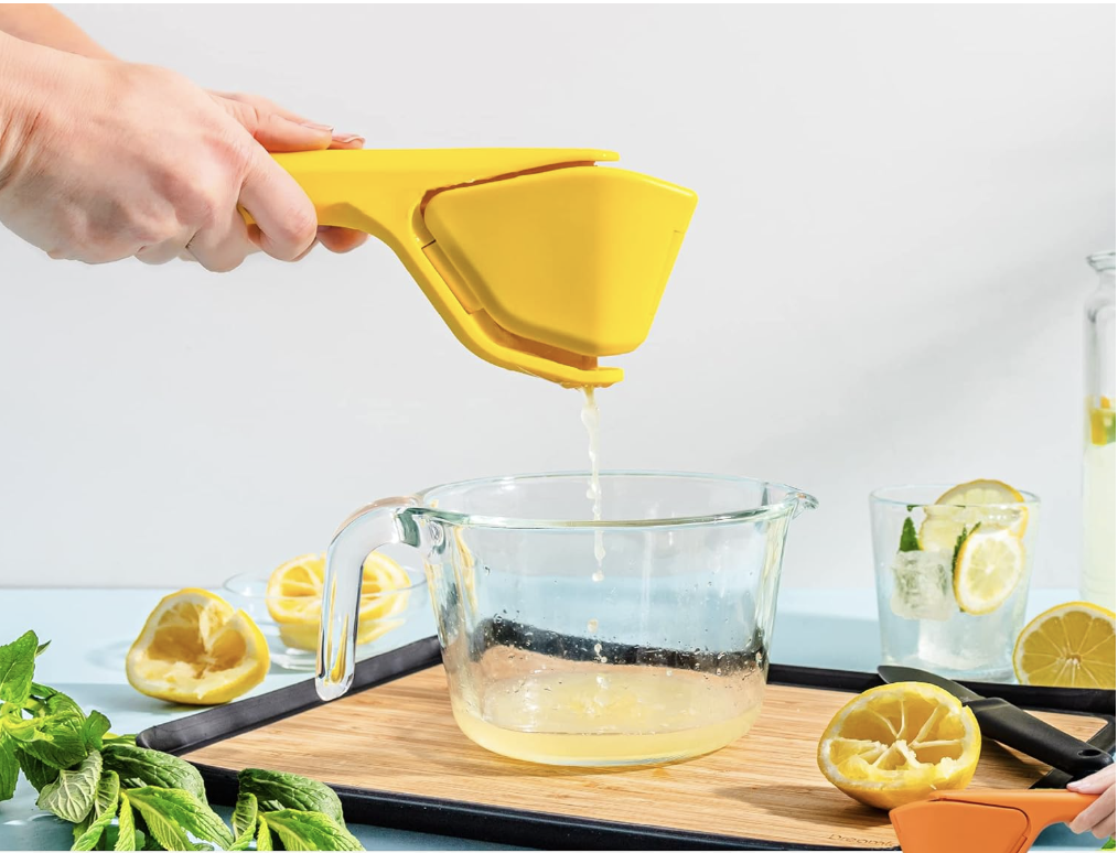 A hand with a juicer held over a glass bowl with lemon juice.