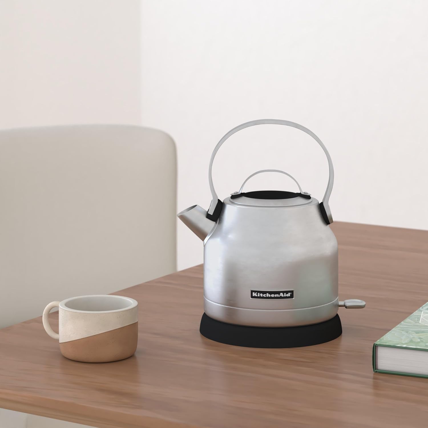 Electric kettle on table between a cup and a book